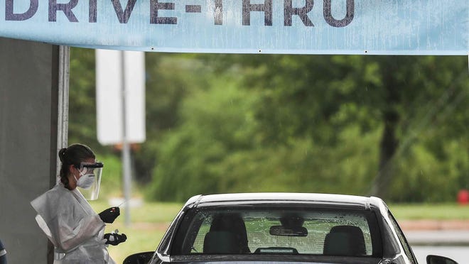 Remedy Urgent Care staff performs the COVID-19 test at a drive-thru test site located at the Toney Burger Center in Austin in May.