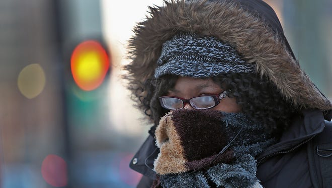 Veronika Joseph stays warm by keeping covered as she waits for the bus at 14th Street and Meridian, Wednesday, January 7, 2015,  A dangerous drop in temperatures and bitter wind chill hit Indianapolis this morning.