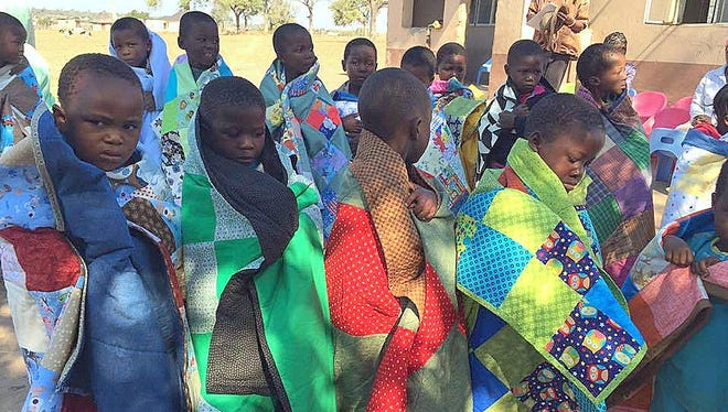 Children from the African nation of Swaziland show off sleeping mats quilted by groups in Elmira and Corning.