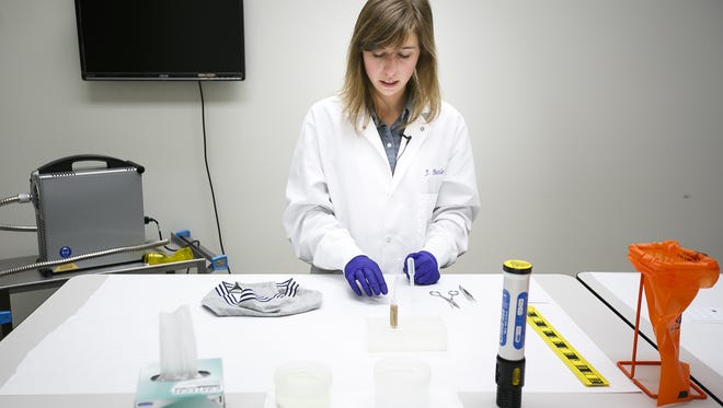 Forensic scientist Jennifer Buttler cuts small pieces of cloth from a sample piece of underwear as she demonstrates the steps required to process a sexual assault forensic evidence kit on Thursday, May 25, 2017, at the Oregon State Police Forensics Services Division.