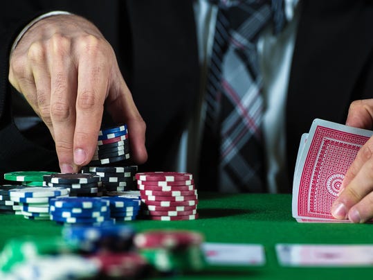 Businessman with hand of cards and selecting casino chips