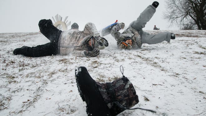 Aiden Lafuente, 12, left, looses a boot as his brother Frankie, 11, crashes into him as they sled down a hill by the capitol on Friday, Dec. 29, 2017, in Des Moines.