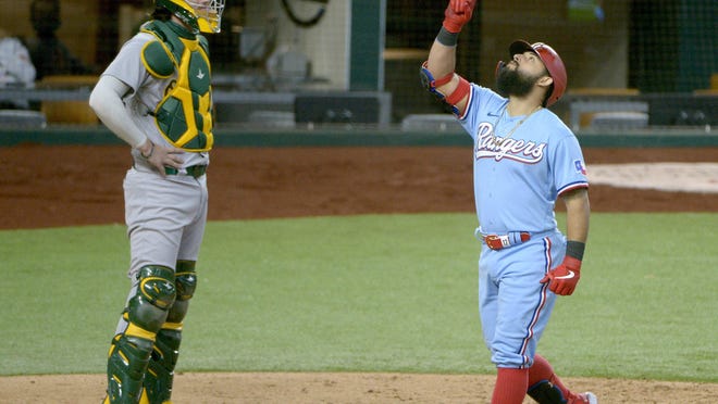 Texas Rangers' Rougned Odor celebrates as he touches home plate after hitting a three-run home run in the Rangers' 6-3 win over the Oakland A's Sunday in Arlington. A's catcher Jonah Heim, left, looks on.