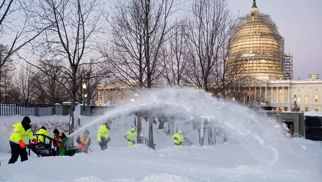 Employees of the Architect of the Capitol clear snow from the Capitol grounds at dawn, following this weekend's blizzard in Washington, D.C, on Jan. 24, 2016.