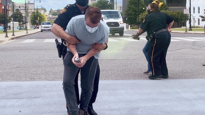 Police arrest protesters who were attempting to spray paint "Good Trouble" and "Expand Medicaid" on the street in front of the Alabama Capitol on Tuesday, July 28, 2020, in in Montgomery, Ala. The group held a news conference earlier urging the state to expand its Medicaid program as most states have done.