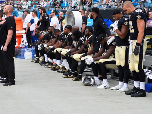 Saints players sit during the national anthem in Week