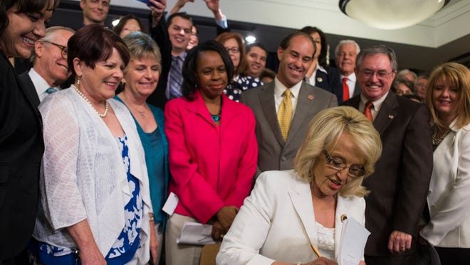 Gov. Jan Brewer signs Medicaid expansion legislation at the Arizona State Capitol on June 17, 2013.