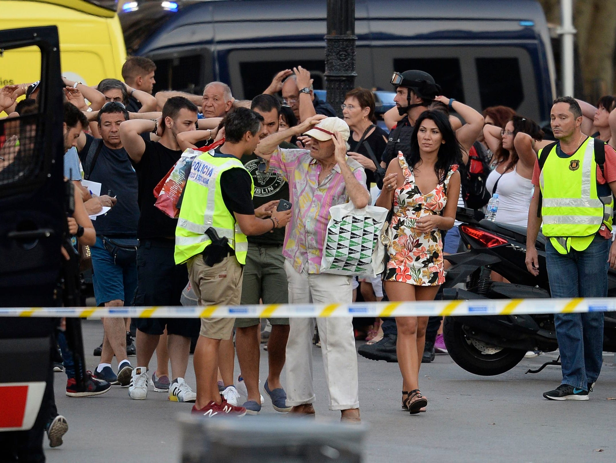 Policemen check the identity of people standing with their hands up in Barcelona on Aug. 17, 2017.