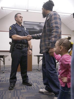 Lavonte Dell, holding 3-year-old daughter Lauren's hand, thanks Westland Police Officer Joshua Scaglione for his act of kindness in this 2016 file photo.