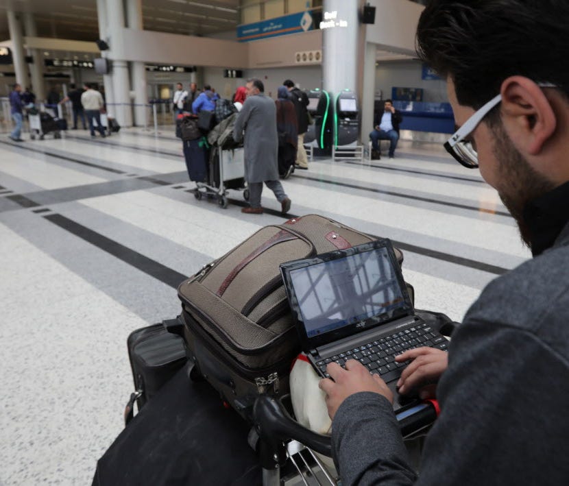 A Syrian passenger travelling to the United States through Amman types on his laptop before entering Beirut International Airport's departure lounge on March 22, 2017.