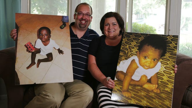 Kevin and Dawn Schafer of West Des Moines hold photos of their adopted children, Zander and Emma, two Congolese children who are being held in the African country due to political complications with adoption policies with the United States.