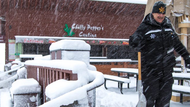 A worker walks past heavy snowfall on the deck of the Lodge at Big Springs Monday, in Truckee, Calif.