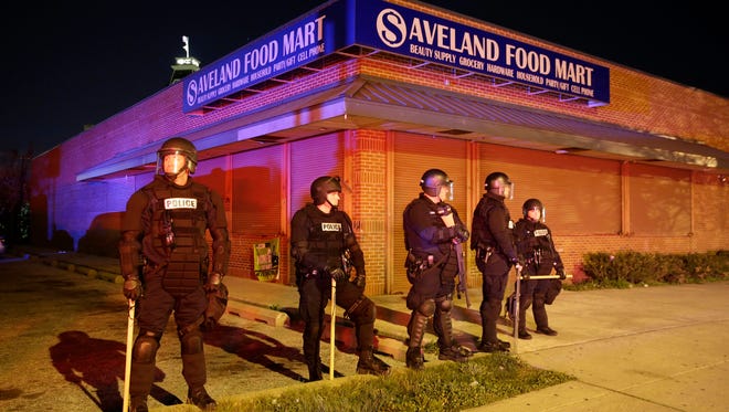 Police stand outside a shuttered store, Monday, April 27, 2015, during unrest following the funeral of Freddie Gray in Baltimore. Rioters plunged part of Baltimore, torching a pharmacy, setting police cars ablaze and throwing bricks at officers. (AP Photo/Patrick Semansky)