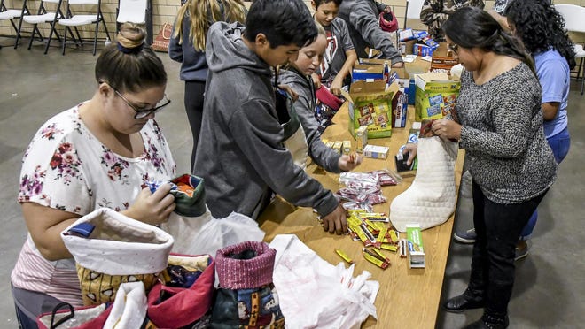 A group of volunteers fill extra Christmas stockings with items and wrap them in plastic bags for shipment Tuesday at the American Legion during the annual Travis Bachman Memorial Christmas Stocking Drive. The filled stockings are shipped to military service members serving overseas during the holiday season. This year's event will be a drive-thru event due to the COVID-19 pandemic.