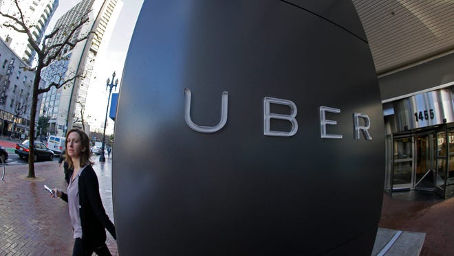 FILE--In this file photo taken, Dec. 16, 2014, a woman leaves the headquarters of Uber in San Francisco, Calif.  The Portland, Ore., City Council is expected to OK allowing Uber to operate legally while removing fare limits for traditional taxi companies with Uber drivers getting background checks and insurance. (AP Photo/Eric Risberg, file)