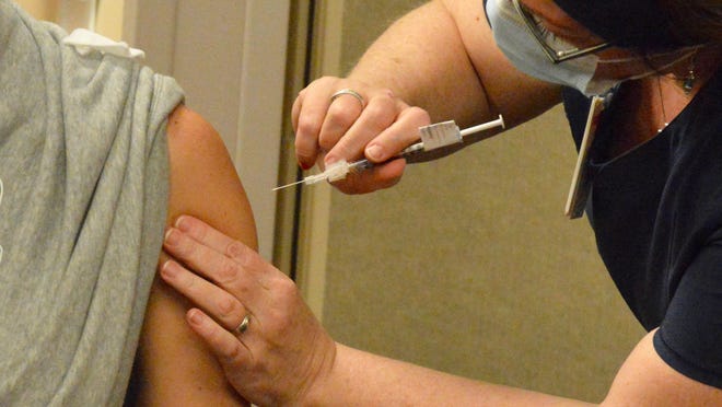 A Holland Hospital nurse administers the COVID-19 vaccine to a hospital staff member Friday, Dec. 18.