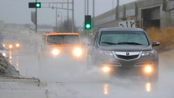 Vehicles travel through standing water on a street in Glendale, Wis., Tuesday, Feb. 20, 2018. A storm system stretched from Texas to the Great Lakes states and forced some schools to close. The National Weather Service issued winter weather advisories for parts of Oklahoma, Kansas, North Dakota, Missouri, Iowa, Minnesota and Wisconsin. Flood warnings were in effect in Illinois, Indiana and Michigan with flood watches in Texas and Arkansas.