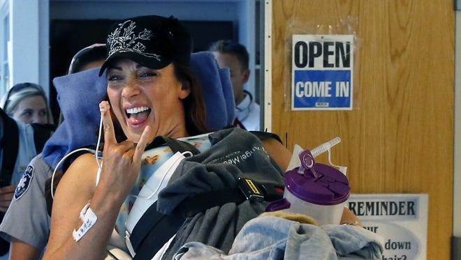 In this June 18, 2014 file photo, six-time Olympic gold medal swimmer Amy Van Dyken-Rouen smiles and gestures as she is transferred to her room after arriving at Craig Hospital, in Englewood, Colo.