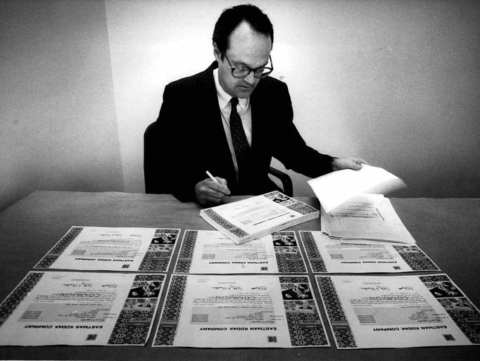Marshall Carter, an executive vice president of Chase Lincoln First Bank, puts his signature on another Eastman Kodak Co. certificate. The most popular players in baseball probably didn't sign as many autographs this month as Carter and other officers of the bank signed yesterday and today. Dashing off 1,000 at a sitting they worked their way through 160,000 stock certificates for Eastman Kodak C. The certificates will be mailed to stockholders Oct. 19 as part of the bank's role in Kodak's 3-for-2 split. The law allows the use of printed signatures for Kodak corporate officers, but requires a hand-written signature by a bank officer to validate each certificate. So from time-to-time, the bank's stock transfer department organizes check-signing "parties" with 20 or more guests at a time. Barring writer's cramp, the chore usually takes about 90 minutes. Officers with short names ofter get to leave early. (Steve Purcell photo, 10/5/1987)
TU 10/6/1987