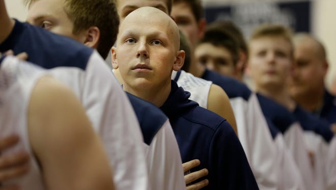 Ryan Dieringer covers his heart during the playing of the National Anthem at the beginning of the Columbus Catholic game against Athens March 1, 2016. Dieringer attended the game to cheer on his team after a year-long battle with cancer that ended when he was given a diagnosis of "no evidence of disease."