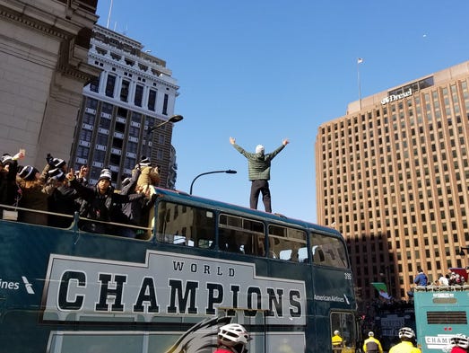 A Philadelphia Eagles fan stands on top of a bus during