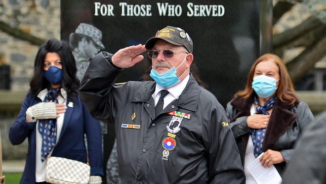 Henry "Hank" Mello salutes during the singing of the National Anthem at the rededication ceremony of the Taunton Desert Shield/Desert Storm monument, Sunday Nov. 1, 2020.