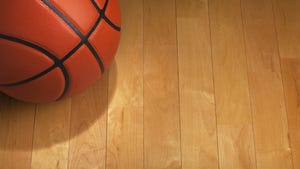 Basketball with spot lighting on wood gym floor