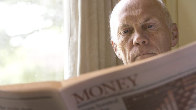 A senior man reading the money section of a newspaper.