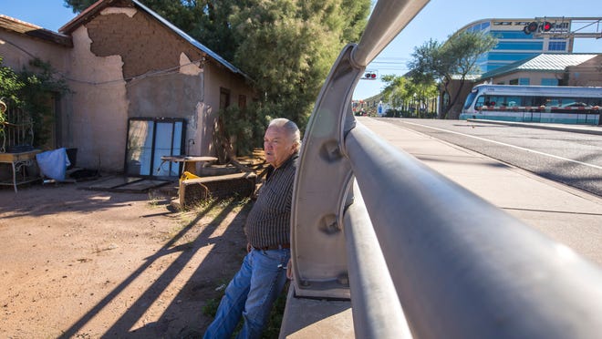 A light-rail train rolls past the property of Steve Sussex on Monday, Oct. 13, 2014. The land appears like a junkyard filled with a couple of hand-made buildings weathered by time, a bus, a cab of a semi-truck, assorted pieces and parts, lumber and bricks. But it is part of his Tempe birthright. Tucked away in the lot is an adobe home, on the corner of Farmer Avenue and 1st Street, that his great-grandfather built in the late 1800s, one the city deems historic. Sussex is battling the state, and will most likely battle the city of Tempe soon, on whether his family gets to keep it.