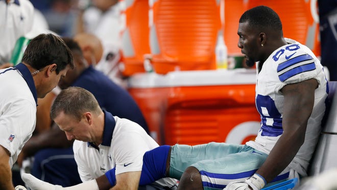 Dallas Cowboys receiver Dez Bryant (88) gets his right ankle worked on by trainers while on the bench in the fourth quarter against the New York Giants at AT&T Stadium.