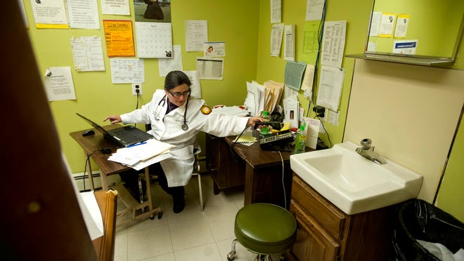 Dr. Lesly D'Ambola, D.O., does paperwork in between appointments in one of the exam rooms at St. Luke's Catholic Medical Center in Camden on Wednesday, May 7, 2014. Because space in the office is so tight, Dr. D'Ambola doesn't have a private office in the practice and uses one of the exam rooms as such. The office, located on State Street in North Camden, has been in practice for approximately 30 years and serve the mostly poor and/or uninsured community, allowing patients to pay what they can, when they can.
