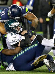 Eagles quarterback Carson Wentz (11) is sacked by Seattle's Sheldon Richardson (91) and Frank Clark (bottom) Sunday night in the Eagles' 24-10 loss.