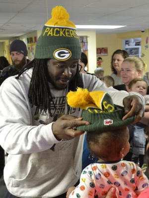 Green Bay Packers running back Eddie Lacy puts a Packers knit hat on the head of 6-month-old Derrick Dobbs Jr. during Lacy's surprise visit to the Freedom House Ministries Family Life Advancement Center in Green Bay on Saturday.