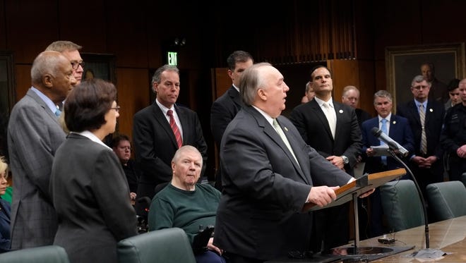 With the MSU Board of Trustees at his side, former Michigan governor John Engler makes a statement at the Trustees meeting Wedneday, Jan. 31, 2018 in East Lansing, Michigan. John Truscott, Engler's former press aide in the governor's office, is seen two people to the right of Engler in the blue tie.