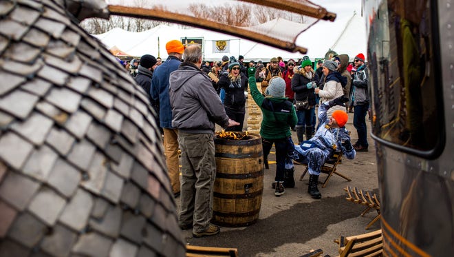 Festival goers form around a fire pit to keep warm at the New Holland Brewing Company area during the 11th annual Winter Beer Festival in Comstock Park, Mich., Friday, Feb. 26, 2016.