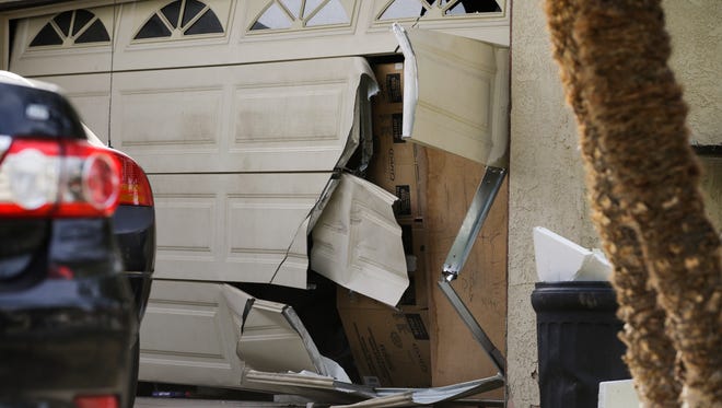 A garage door of Enrique Marquez's home is seen broken in a recent FBI raid, Wednesday, Dec. 9, 2015, in Riverside, Calif. Authorities have said Enrique Marquez, an old friend of San Bernardino attacker Syed Farook, purchased two assault rifles used in last week's fatal shooting that killed 14 people. (AP Photo/Jae C. Hong)