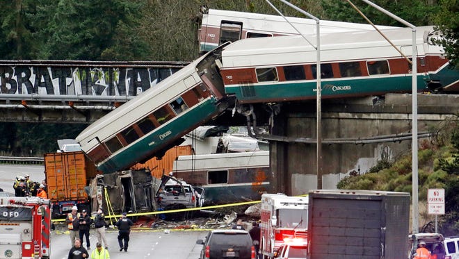 Cars from an Amtrak train lay spilled onto Interstate 5 below alongside smashed vehicles as some train cars remain on the tracks above Monday, Dec. 18, 2017, in DuPont, Wash. The Amtrak train making the first-ever run along a faster new route hurtled off the overpass Monday near Tacoma and spilled some of its cars onto the highway below, killing some people, authorities said. Seventy-eight passengers and five crew members were aboard when the train moving at more than 80 mph derailed about 40 miles south of Seattle before 8 a.m., Amtrak said.