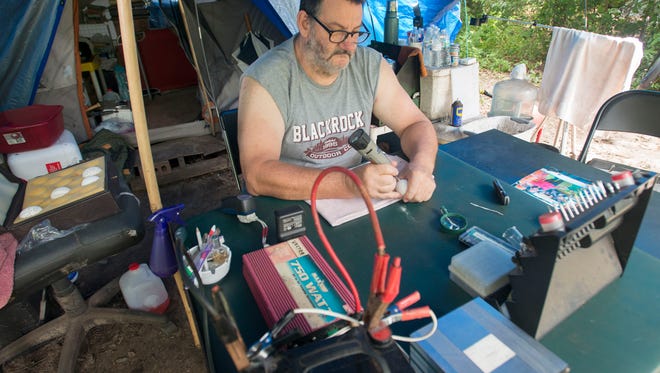 Sean's Outpost resident, known as Russell, works on an art project outside his campsite in the Satoshi Forest off Massachusetts Ave. Russell has lived at the Sean's Outpost for nearly a year.