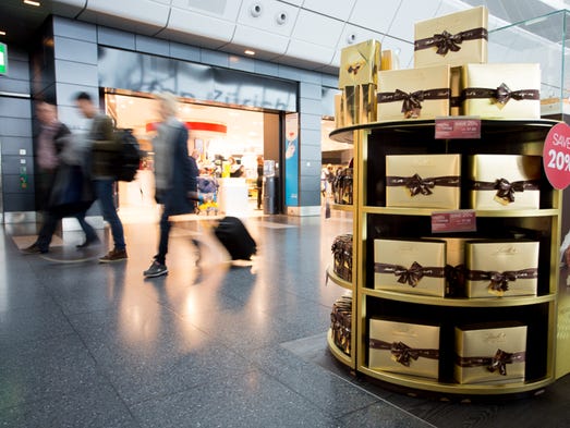 Passengers walk past a Lindt Swiss chocolate display