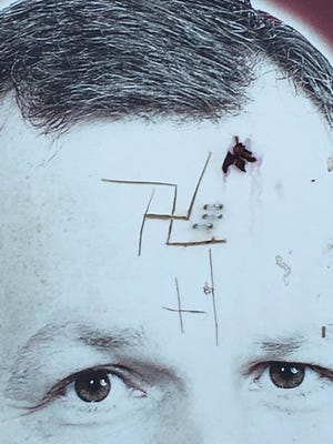 A swastika is carved into the forehead of a loan officer featured on a billboard sign outside a bank in Hurricane.