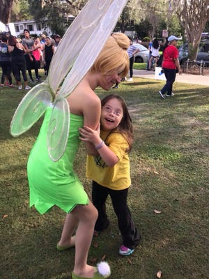 Tinkerbell (Georgieanna Gross) hugs a child at a Buddy Walk for Down Syndrome as a member of the Guardians of Justice.