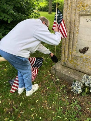 Volunteer Peggy Masciulli plants a flag at a veteran's gravesite Saturday.