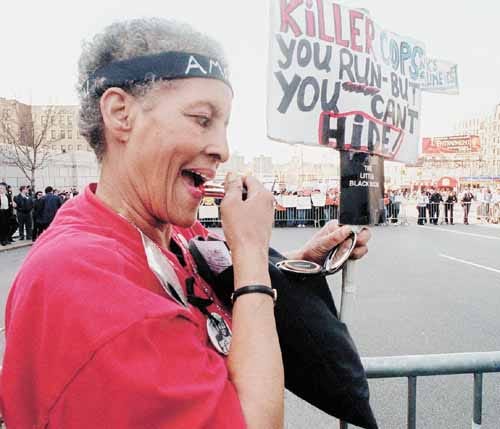 Protester Carol Taylor pauses for a moment to freshen up her lipstick during the all-day demonstration against police brutality outside the State Supreme Courthouse in the Bronx borough of New York on Wednesday, March 31, 1999. Four white police officers were indicted on second-degree murder charges Wednesday in the shooting of unarmed immigrant Amadou Diallo.