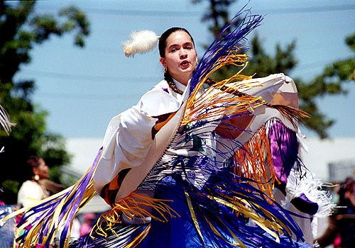The wind catches the fringes of a shawl dancer's costume, above, at the Mashpee Wampanoag Powwow yesterday. Dancers, below, chant a song as they circle the dance arena at the Barnstable County Fairgrounds.
