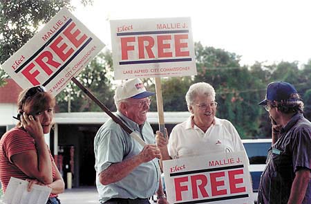 Mallie J. Free, second from left, chats with supporters outside Lake Alfred city hall Tuesday during voting hours.