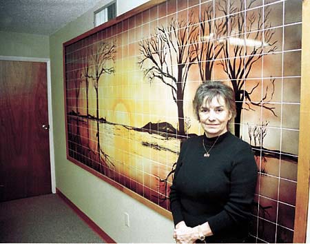 Artist Pati Mills stands in front of a mural created by her for Dr. Howard Luca's office waiting room in Winter Haven.