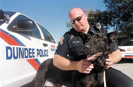 Chief Dundee Police Officer Josh Willets kneels with Kimba, the latest addition to the Dundee Police Department.
