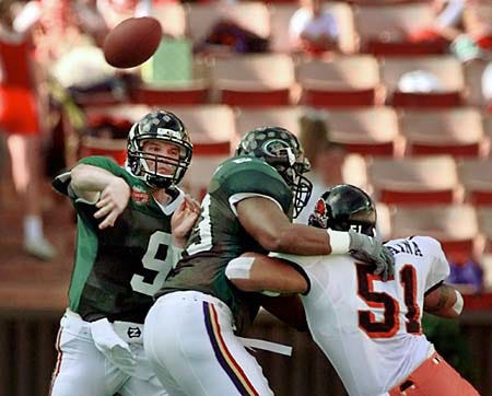Hawaii quarterback Dan Robinson (9) tosses in the second quarter, as teammate Sean Butts holds back Oregon State's Toalei Talataina (51) at the Oahu Bowl on Saturday in Honolulu, Hawaii.