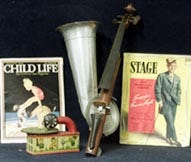 An amplified violin used for early sound recordings rests alongside some old music magazines and a toy gramophone as part of the Ben Thacher music collection that will be auctioned at the Atlantic Auction Gallery in Sagamore tomorrow.