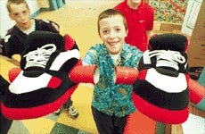 Alex Anthony, a fifth-grader at Frisbee Elementary School in Kittery, holds up his invention, Mega Slippers, at the school's Invention Convention 2000 yesterday.
Staff Photo by